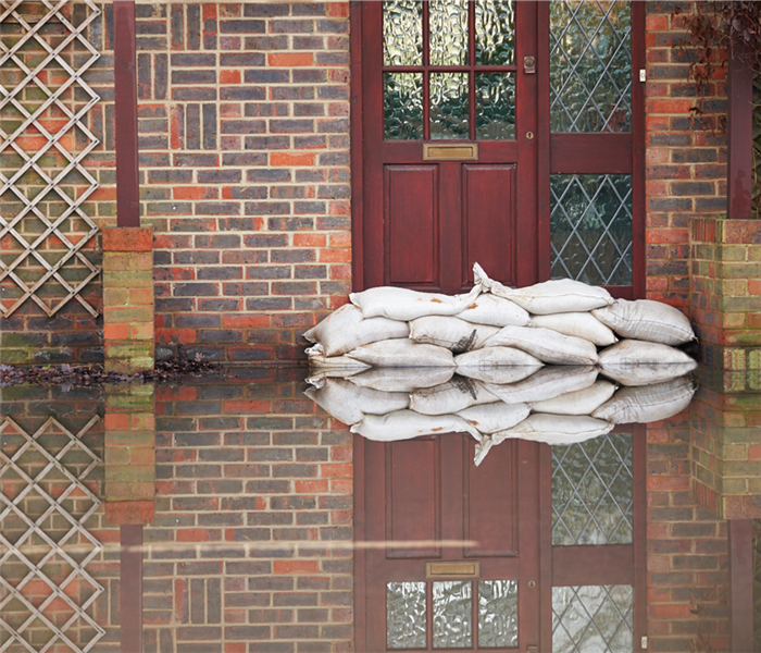 Flooding outside home and sandbags in front of the door.