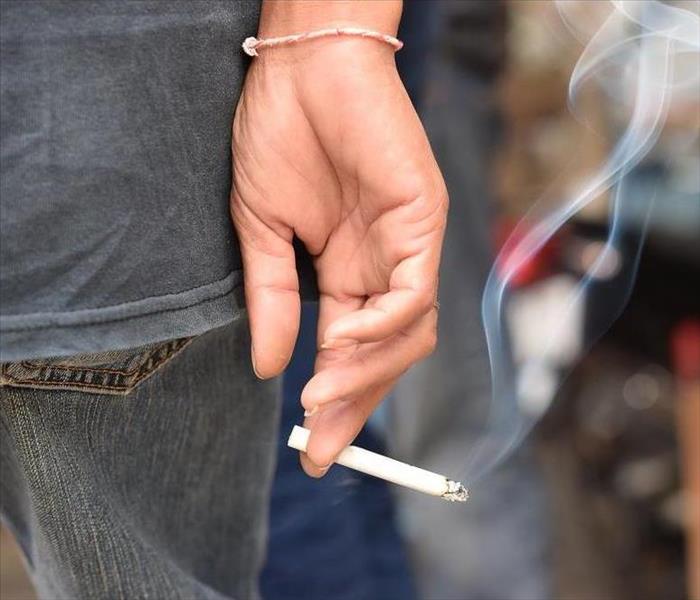 Lit cigarette held by a woman's hand.