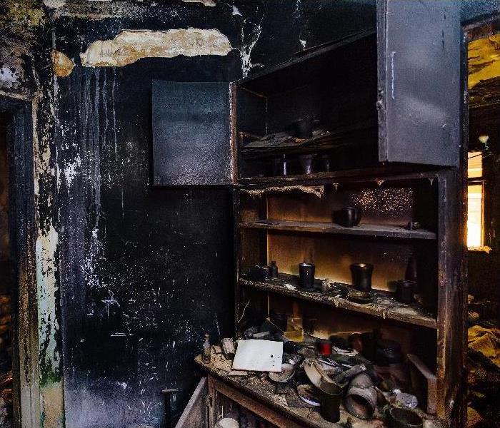 Burnt house interior. Burned furniture, kitchen cabinet, charred walls and ceiling in black soot.